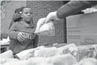  ?? MAX GERSH/THE COMMERCIAL APPEAL ?? Fifth-grader Josiah Johnson, 10, is handed a bagged lunch by Ruby Buckner of the YMCA of Memphis and the Mid-south in March 23 at the Ed Rice Community Center in Memphis.