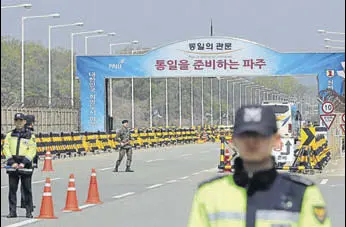  ?? AP ?? South Korean police officers and a soldier stand at Unificatio­n Bridge, which leads to the truce village of Panmunjom in Paju, South Korea, on Wednesday.
