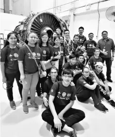  ??  ?? Students pose with an aircraft engine used for training purposes.