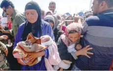  ?? — AFP ?? Displaced Iraqis, who fled the northern city of Mosul due to the government forces military operation to retake the city from IS group fighters, wait to receive food aid at Al Khazar camp in the village of Hasan Sham, east of Arbil.