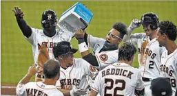  ?? BOB LEVEY/GETTY ?? Yuli Gurriel dumps ice on Astros teammate Myles Straw after his game-winning single.