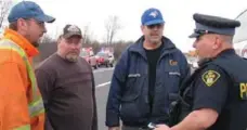  ??  ?? From left, Jeremy Hager, Darrin Martin and George Bailey speak with a police officer after rescuing a man from an SUV that crashed on the QEW.