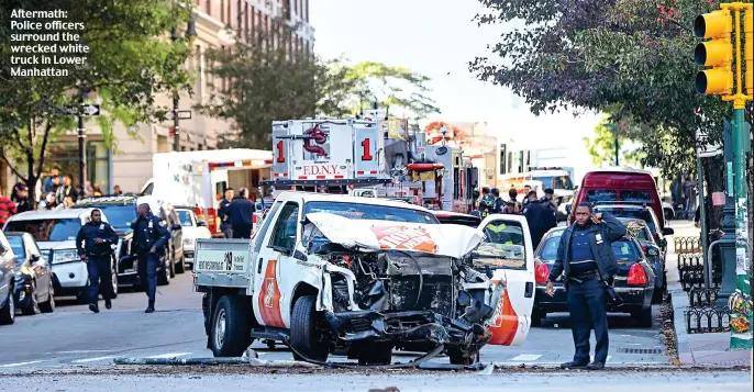  ??  ?? Aftermath: Police officers surround the wrecked white truck in Lower Manhattan