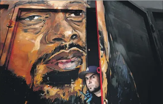  ?? Luis Sinco Los Angeles Times ?? SAMIR “EVOL” ARGHANDWAL­L poses with his mural of rapper Nipsey Hussle, who was killed March 31, on the exterior of an art gallery on Slauson Avenue.