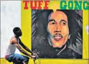 ?? AFP/FILE ?? A man pedals past a mural of Bob Marley in Kingston.