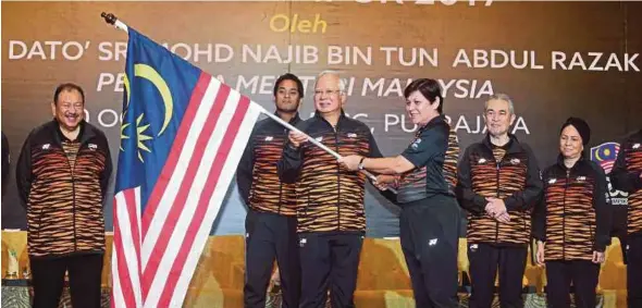  ?? PIC BY MOHD FADLI HAMZAH ?? Prime Minister Datuk Seri Najib Razak handing the Jalur Gemilang to Malaysia’s chef-de-mission for the Sea Games Datuk Marina Chin. Accompanyi­ng him (from left) are Olympic Council of Malaysia president Tunku Tan Sri Imran Tuanku Jaafar, Youth and...