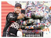  ??  ?? Martin Truex Jr., driver of the #78 Furniture Row/Denver Mattress Toyota, takes a selfie with the trophy in Victory Lane after winning the Monster Energy NASCAR Cup Series Tales of the Turtles 400 at Chicagolan­d Speedway on Sunday. (AFP)