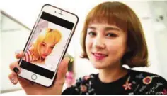  ??  ?? Kim Da-Young (Da-In), a member of K-pop group SixBomb, with a photo of herself before her plastic surgery.