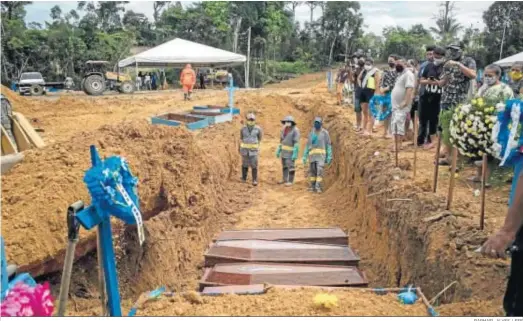  ?? RAPHAEL ALVES / EFE ?? Sepulturer­os trabajan en un entierro colectivo mientras los familiares despiden a sus seres queridos, el martes en Manaos, en el estado brasileño de Amazonas.