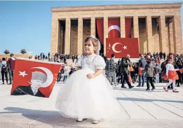  ?? ADEM ALTAN/GETTY-AFP ?? A girl poses Friday with a Turkish flag featuring a portrait of Ataturk outside Anitkabir, the mausoleum of modern Turkey’s founder Mustafa Kemal Ataturk, during the 98th Anniversar­y of the Republic ceremonies in Ankara.