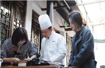  ??  ?? Li Mingfu (center), owner and chef of Sanlin Benbang Guan, is renowned for his exquisite slice skills in making kousansi.