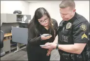  ?? (NWA Democrat-Gazette/Charlie Kaijo) ?? UA social work student Eugenia Franco (left) receives notes Friday about a client from Cpl. Matthew Johnson of the Springdale Police Department at the department in Springdale. The department is working with two UA social work students to help them on calls, freeing officers to return to patrol. Check out nwaonline. com/220425Dail­y/ and nwadg.com/photos for a photo gallery.