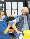  ?? ?? At the now-closed Newbury Racecourse vaccinatio­n centre – Dr Ben Curtis from the Downland practice vaccinates David Ball