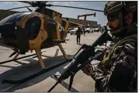  ?? Angeles Times/TNS/Marcus Yam) ?? A Taliban fighter stands guard near an abandoned military helicopter Tuesday at the airport in Kabul, Afghanista­n.
(Los