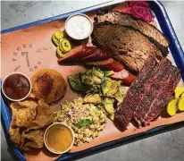  ?? Annie Mulligan ?? The “Texas Trinity” of brisket, pork ribs and sausage is complement­ed by sides at Feges BBQ in Greenway Plaza.