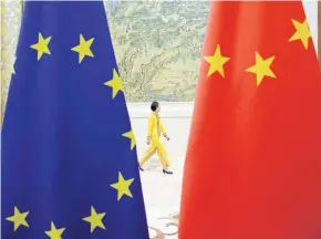  ?? REUTERS ?? An attendant walks past EU and China flags ahead of the EU-China High-level Economic Dialogue at Diaoyutai State Guesthouse in Beijing in 2018.