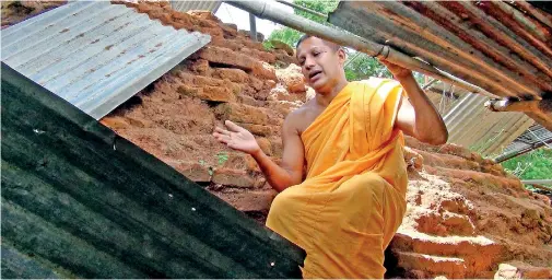  ??  ?? Chief Incumbent Poththukku­lame Dheeranand­a Thero points out the damage to the structure