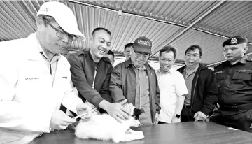  ??  ?? Uggah (centre) together with Dr Sim (third right) witnessing Dr Adrian (left) injecting the anti-rabies vaccine to a dog named ‘Gendut’ at MJC, Batu Kawa yesterday.