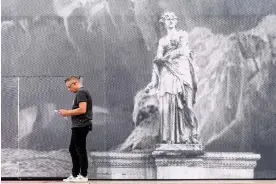  ?? Photograph: Teresa Suárez/EPA ?? Caveman … a man stands next to a representa­tion of Plato’s cave on the facade of the Opéra Garnier in Paris.
