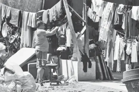  ??  ?? FOR DRYING. A man hangs newly washed clothes outside the Juliville Subdivisio­n gym in Davao City after the sun came out yesterday morning. There are still 97 families are at the gym as rain and dark skies discourage them from going back to their...