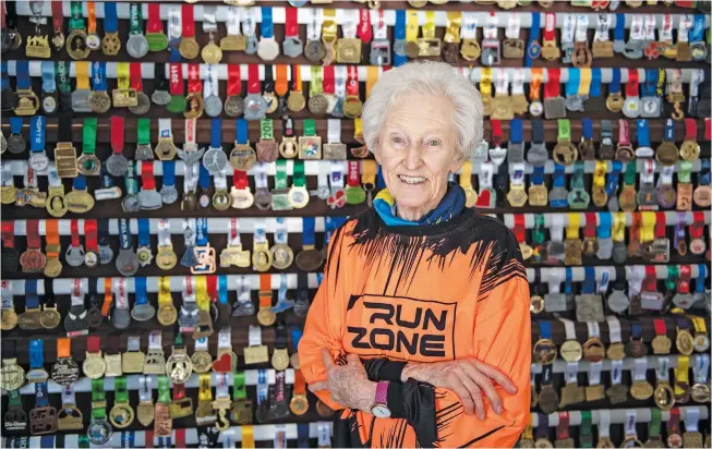  ?? Pictures: Michel Bega ?? WORLD RECORD HOLDER. Road runner Deirdre Larkin, 89, at her home in Randburg, in front of a wall of medals she has won since she took-up the sport 10 years ago.