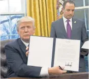  ?? SAUL LOEB, AFP/ GETTY IMAGES ?? President Trump holds up an executive order withdrawin­g the U. S. from the TransPacif­ic Partnershi­p after signing it alongside White House Chief of Staff Reince Priebus.