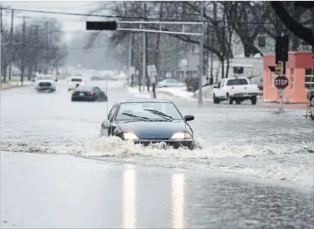  ?? ANGELA MAJOR, THE ASSOCIATED PRESS ?? A vehicle drives through a flooded street on Tuesday in Janesville, Wis.