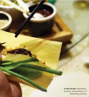  ??  ?? A chef wraps vegetables, pickles, and peanuts in a Shandong jianbing