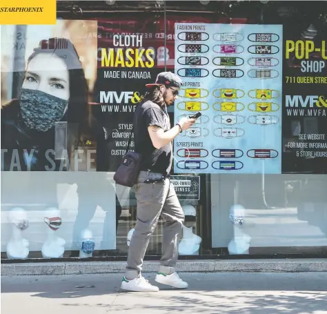  ?? PETER J THOMPSON FOR NATIONAL POST ?? A pedestrian walks past a pop-up mask store on Monday in Toronto, where face-coverings became mandatory in indoor public spaces this week.