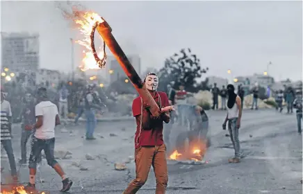  ?? Photo: REUTERS ?? A Palestinia­n protester brandishes a burning object during clashes with Israeli troops near Ramallah, following a series of fatal attacks on Israelis.