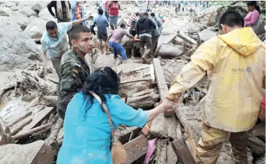  ?? PICTURE: AP ?? HELPING HANDS: Soldiers and rescue workers evacuate residents from the area in Mocoa, Colombia, after an avalanche of mud from an overflowin­g river swept through the city as people slept.