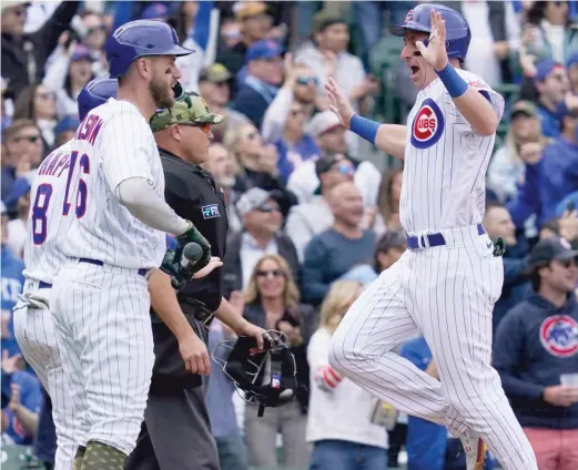  ?? AP ?? The Cubs’ Frank Schwindel (right) celebrates with Patrick Wisdom and Ian Happ after scoring on a three-run triple by P.J. Higgins in the second inning Sunday.