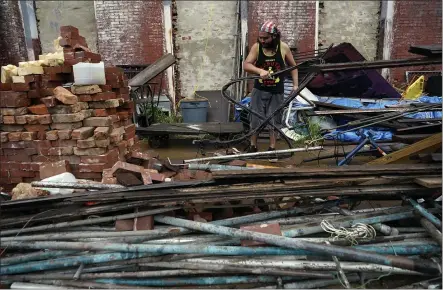  ?? DAVID J. PHILLIP — THE ASSOCIATED PRESS ?? Adrian Bentancour­t cleans up debris from a fence in Galveston, Texas, that was blown down by Hurricane Nicholas on Tuesday.