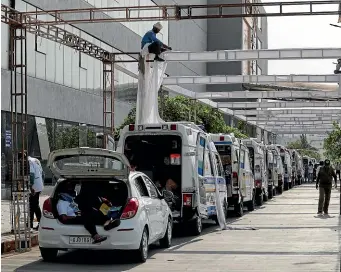  ?? AP ?? Ambulances carrying Covid-19 patients wait for their turn to be attended outside a government hospital in Ahmedabad as a worker erects a sun shade.