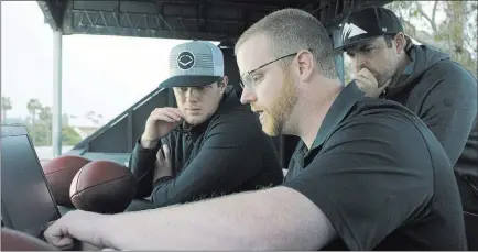  ?? Wilson Sporting Goods ?? The Associated Press Sam Darnold, left, and mentor Jordan Palmer, right, watch as Wilson Labs engineer Dan Hare explains data gathered from passing using the Wilson Connected Football System.