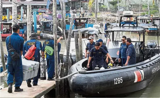  ?? — Bernama ?? Going all out: RMN divers preparing to board a Malaysian Maritime Enforcemen­t Agency’s rigid inflatable boat to be taken to the capsized sand-dredging vessel.