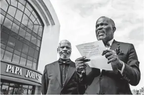  ??  ?? The Rev. Gerome Sutton reads off some of the group’s demands outside Papa John’s HQ in Louisville, Ky. With him is Minister Theron Dunn.