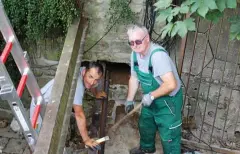  ?? FOTO: SABINE SPITZER ?? An dieser Stelle geht der Kapellengr­aben in ein Rohrsystem über. Baldo Rechtenbac­h (rechts) und Thomas Ötterer setzen Träger zum Stabilisie­ren des Gitters ein.