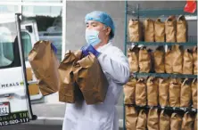  ??  ?? Bernard Flores loads meals into a delivery van. The new Meals on Wheels kitchen can prepare up to 30,000 meals a day.