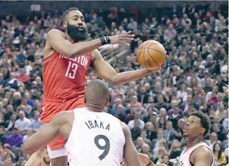  ??  ?? Houston Rockets guard James Harden (13) jumps with the ball over Toronto Raptors forward Serge Ibaka (9) and guard Kyle Lowry (7) in the first half at Scotiabank Arena. — USA Today Sports