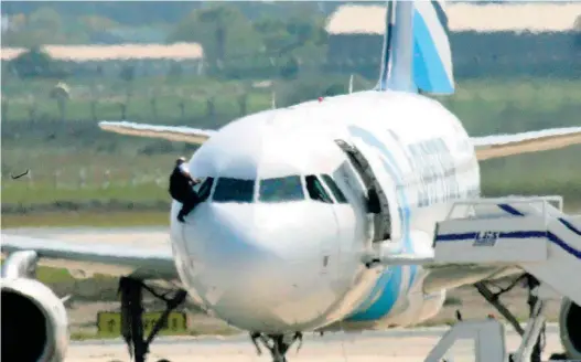  ?? (foto Epa, Afp) ?? La giornata Un membro dell’equipaggio fugge dal finestrino della cabina di pilotaggio. A fianco il dirottator­e posa con un viaggiator­e. In basso 3 passeggeri liberati