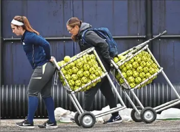  ?? Matt Freed/Post-Gazette photos ?? Infielder Brittany Knight, left, helps new Pitt coach Jodi Hermanek wheel carts of softballs out for batting practice earlier this week.