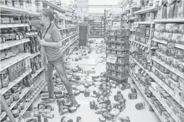  ?? David Bitton / News Press ?? Talia Pershall puts syrup back on a shelf while cleaning up Saturday at White’s Foodliner in Pawnee, Okla., after the 5.6-magnitude earthquake that hit the area.