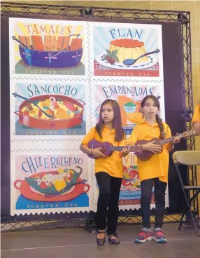  ?? GREG SORBER/JOURNAL ?? Eight-year-old Coronado Elementary students Emily Chavez, left, and Antonella Aragon sing with Voces de Coronado during the unveiling of the U.S. Postal Service Delicioso Forever stamps at the National Hispanic Cultural Center on Thursday.