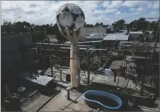  ?? AP PHOTO/RODRIGO ABD ?? A water tank made to look like a large hand holding a soccer ball stands on the roof of a house recalling the famous goal Diego Maradona scored with his hand against England in the 1986 World Cup, in the La Cumbre neighborho­od on the outskirts of La Plata, Argentina on Oct. 18.
