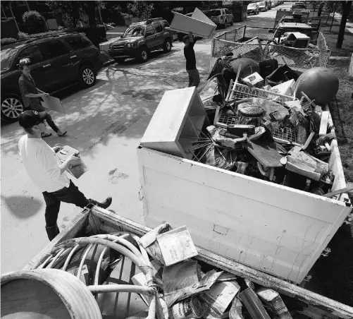  ?? Jonathan Hayward/ THE CANAD IAN PRESS ?? Residents near downtown Calgary load bins with their mud-soaked belongings on Sunday.