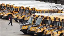  ?? CHARLES KRUPA — THE ASSOCIATED PRESS FILE ?? In this April 27, 2020, file photo, a worker passes public school buses parked at a depot in Manchester, N.H.