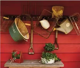  ??  ?? Above: A few of Jona’s favorite vintage farm tools are displayed on the front porch of the couple’s home. To hold the heavy pitchfork, wire baskets and metal items, Jona built her own peg rail using a hefty 2 x 4 with drilled holes and wood dowels. A concrete-coated shovel featuring a nubbly veneer adds to the layered vignette. Jona’s homemade ivy topiary is planted in a vintage enamel bucket that sits in an enamel pan. By cutting a circular hole in a beloved barn-sale table, the base of the top-heavy topiary rests safely below the tabletop.