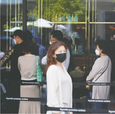  ?? KIM HONG-JI / REUTERS ?? People wearing face masks to avoid the spread of the coronaviru­s disease wait in a line on Friday to get into
a luxury shop at an outlet mall in Gimpo, South Korea.