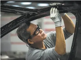  ?? David Butow / Corbis 2015 ?? Workers like this one at Tesla’s Fremont factory will avoid layoffs, which will come “almost entirely” from salaried positions, CEO Elon Musk says.